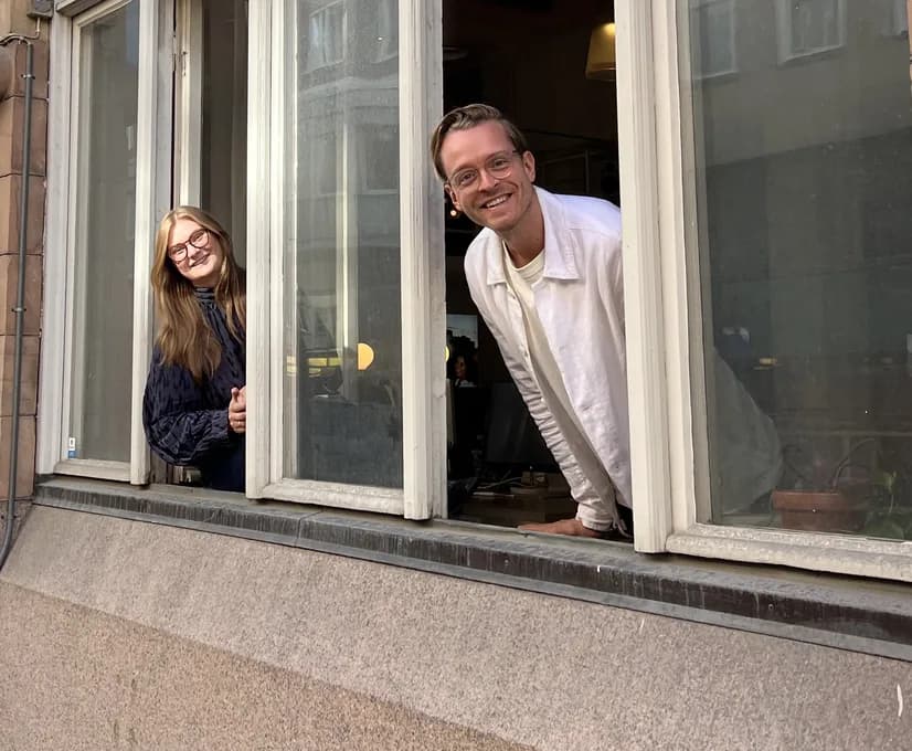 Två personer från Selmas team tittar ut genom ett öppet fönster på kontoret i Stockholm.